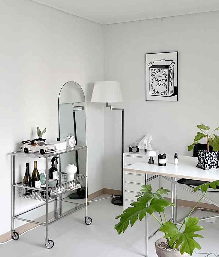 ホワイトトーンの書斎空間、シルバーメタルトロリーとデスク、フロアランプ、緑の植物が配置されたシンプルなインテリア