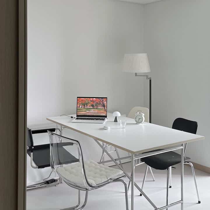 ホワイトトーンのダイニングルーム、大型のダイニングテーブルと椅子が配されたミニマルでモダンな空間