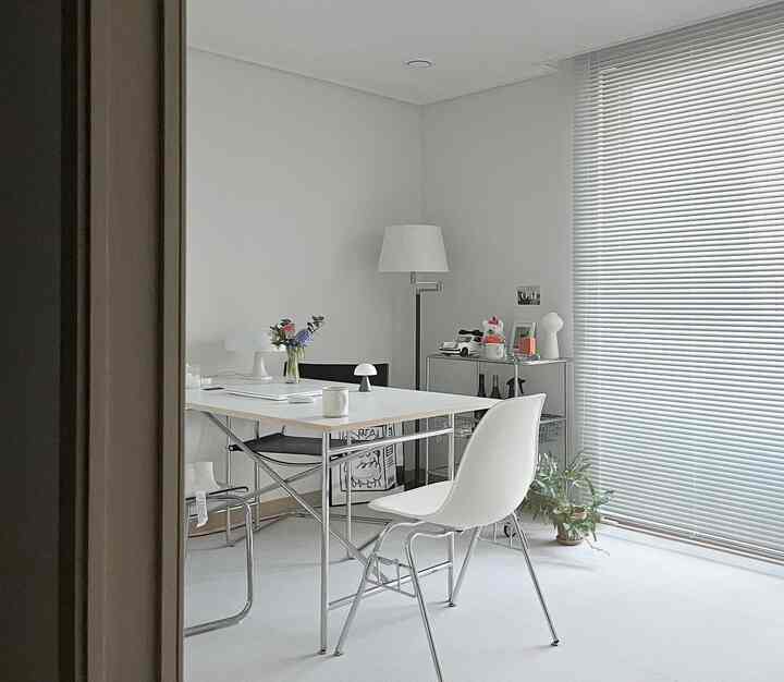 ホワイトトーンのリビング、ミッドセンチュリーモダンスタイルのダイニングテーブルと椅子が配置された清潔で明るい印象的な空間