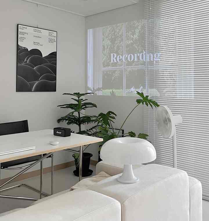 明るいホワイト調のリビング、中央にソファと植物を配置したミニマルモダンなインテリア