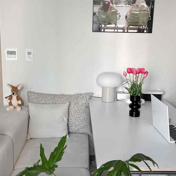 ホワイトとナチュラルな色調のリビングスペース、白いダイニングテーブルとクッション付きソファ、花瓶とテーブルランプが配置された雰囲気のあるインテリア