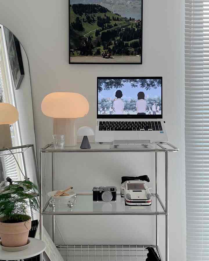 ホワイトとシルバーの色調の空間に、トロリーの上にノートパソコンとランプが配置されたミニマルなホームオフィスのインテリア