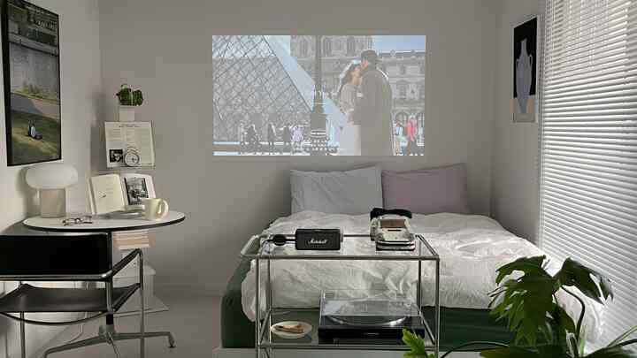 白と緑のトーンの寝室、クイーンサイズベッドとブラインド、小さなおうちカフェコーナーが調和したミニマルなインテリア