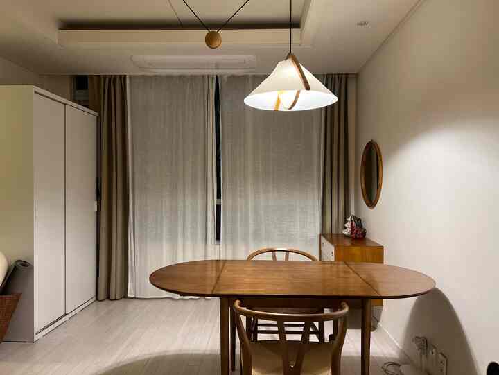 アイボリーと木目調のリビング、木製のダイニングテーブルと椅子、スライド式のワードローブと化粧台が配置されたシンプルで自然な雰囲気のインテリア