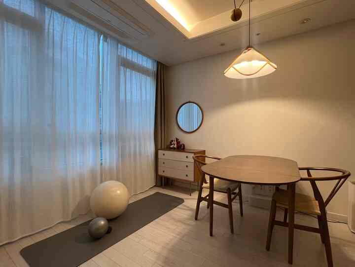 ブラウンとホワイトの落ち着いた2人用ダイニングルーム、大きな窓とヨガマットが置かれた自然な雰囲気の空間