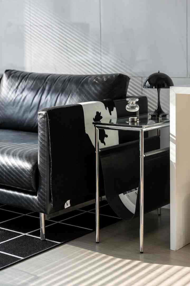 モダンなモノトーンのリビング、レザーソファと柄のスローが置かれたサイドテーブルが配された清潔感のある空間