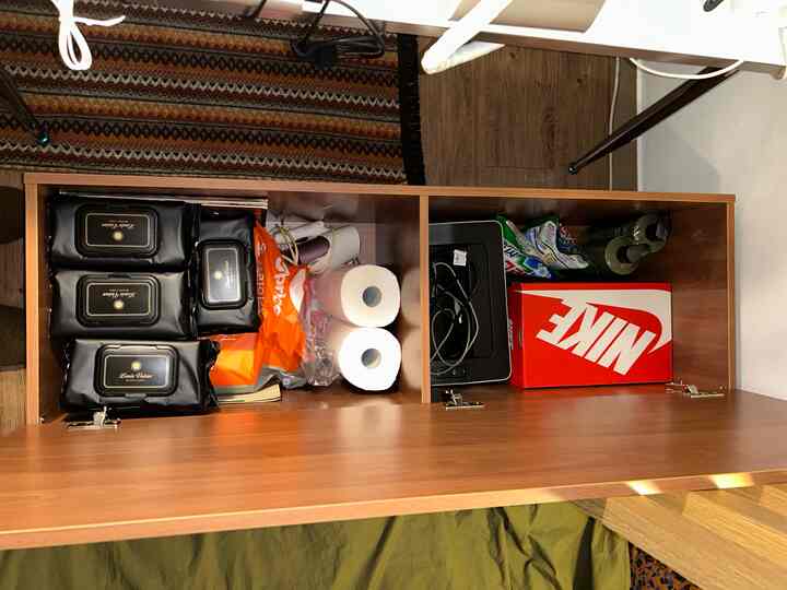 ブラウンの木目調ワンルームの収納ベンチ、生活用品が整然と収納された印象的な空間