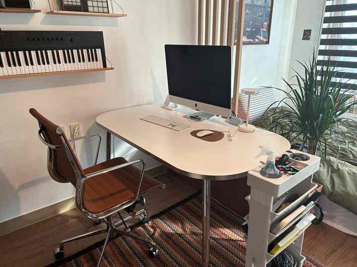 明るいブラウンのレザーオフィスチェアと白いデスクがある、清潔でモダンなホームオフィスの空間