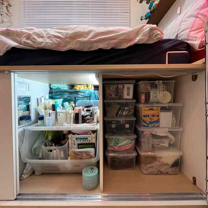 ホワイトとウッドトーンの調和が美しい寝室の収納スペース、透明な収納ボックスとスライディングドアで整理された印象的な空間