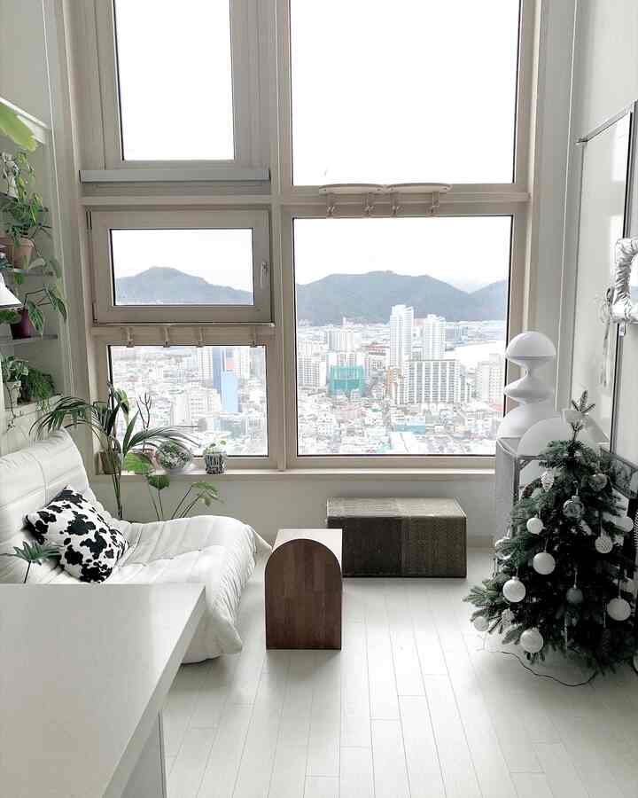 白とナチュラルトーンのリビング、巨大な窓と白いソファ、キャットタワーが配置された雰囲気のある空間