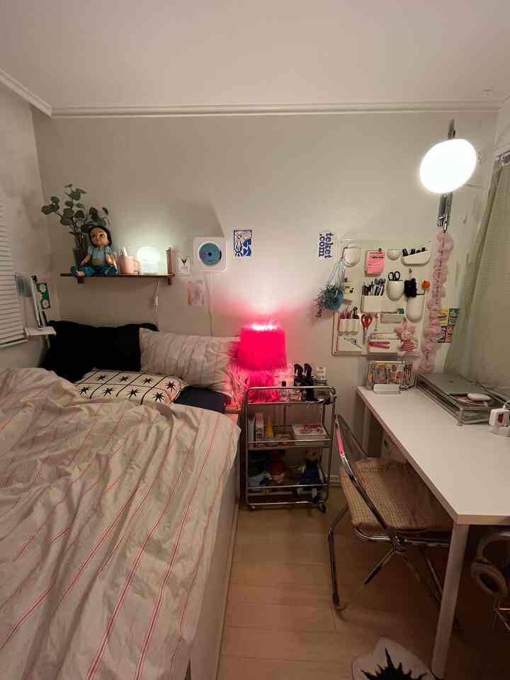 ホワイトとベージュの色調の寝室、快適なベッドとデスク、ピンクのテーブルランプが配置された雰囲気のあるインテリア