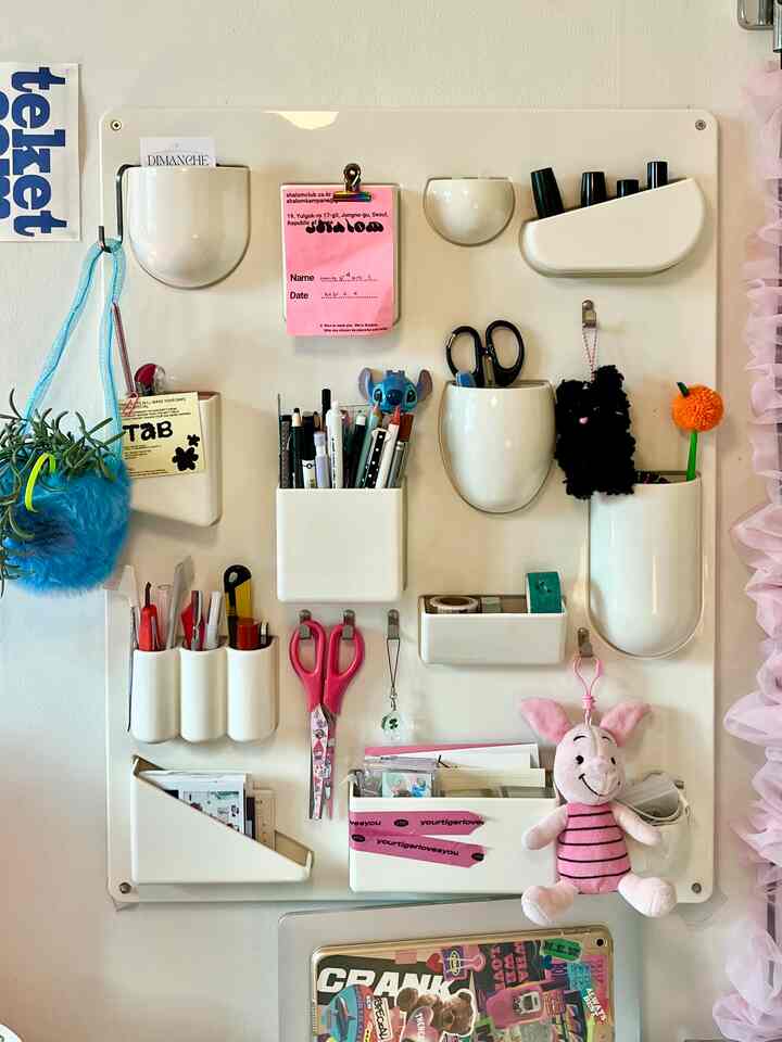 白のオーガナイザーパネルにさまざまな文房具や小物が収納された整理整頓された空間
