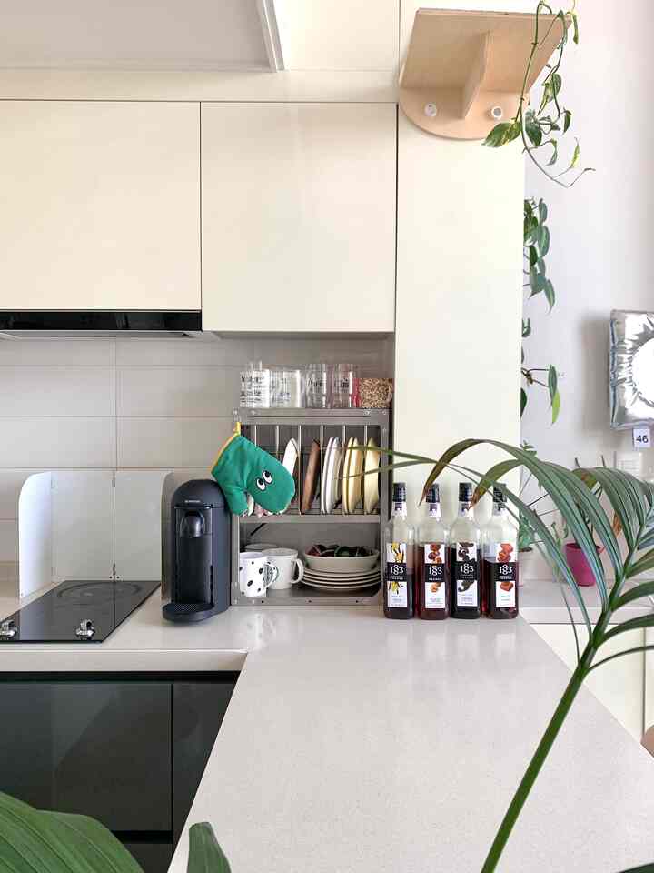 白を基調としたキッチン空間にカプセルコーヒーマシンとキッチンワゴン、植物が配置された清潔感のあるモダンなインテリア