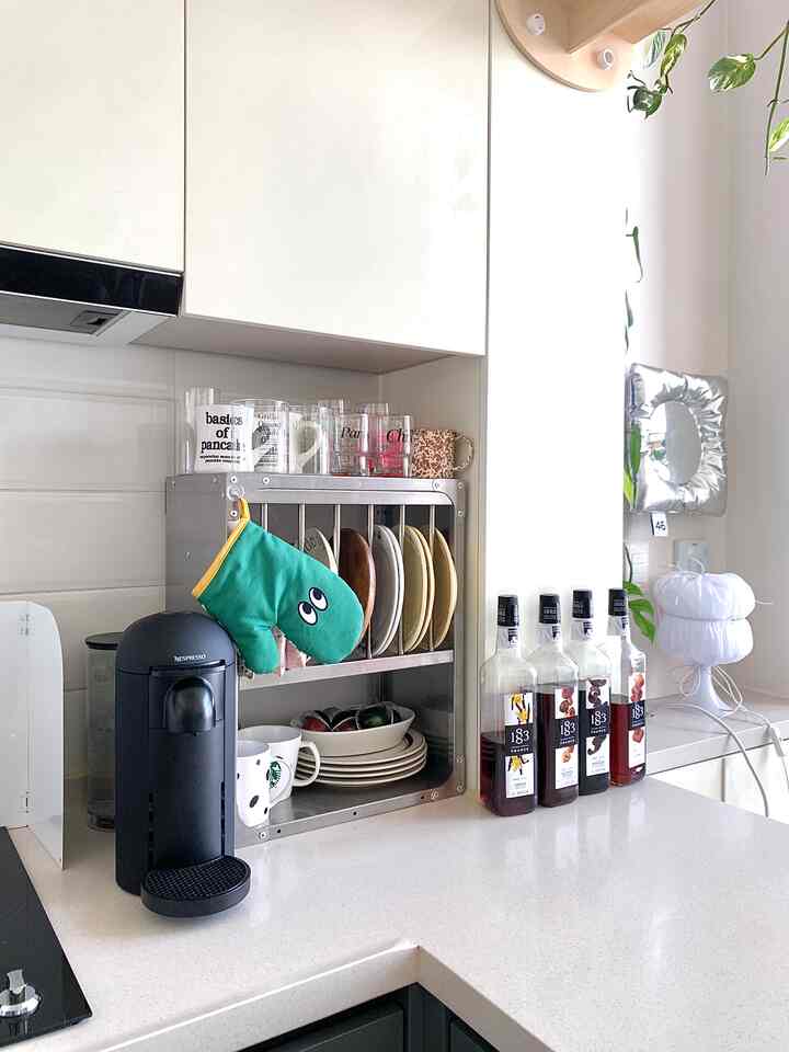 白を基調としたキッチン空間、整然と並んだ皿やマグカップ、コーヒーマシンが置かれた雰囲気のあるおうちカフェ