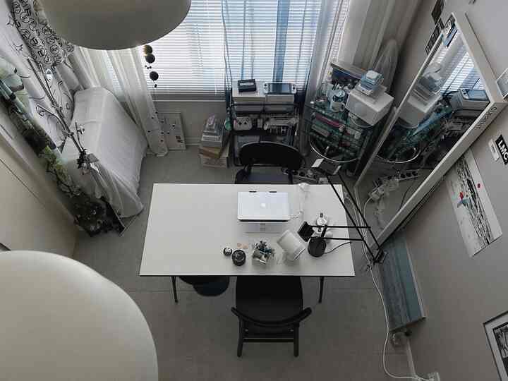 白と黒のトーンでまとめられたコンパクトなホームオフィス、中央に大きなデスクと椅子が配置されたモダンな空間