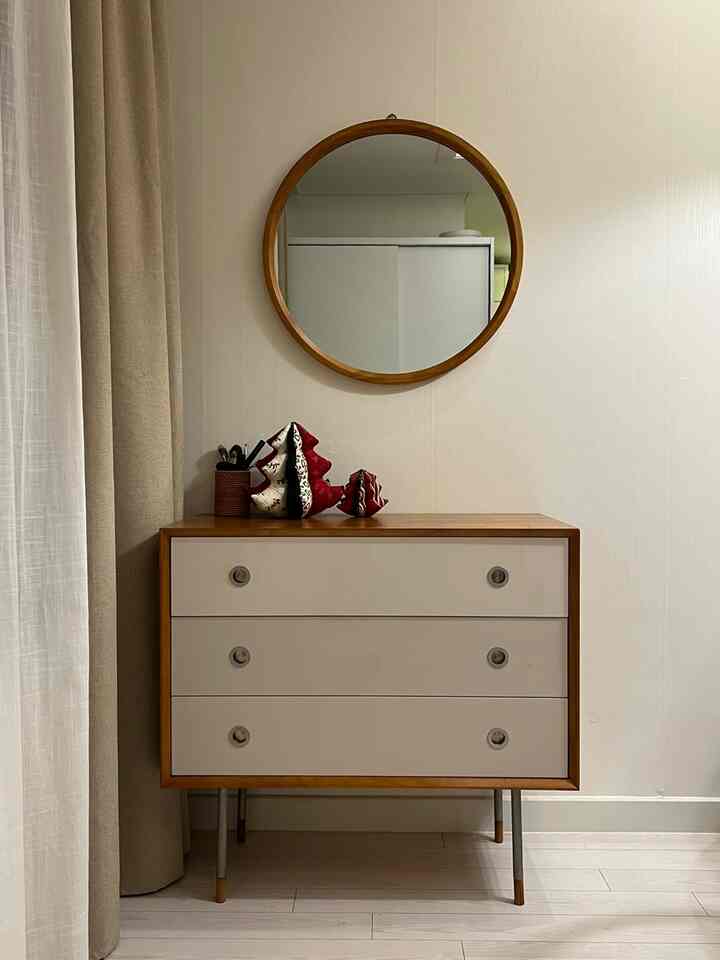 木目調とベージュの落ち着いたパウダールーム、丸い鏡とモダンな化粧台が配置された印象的な空間