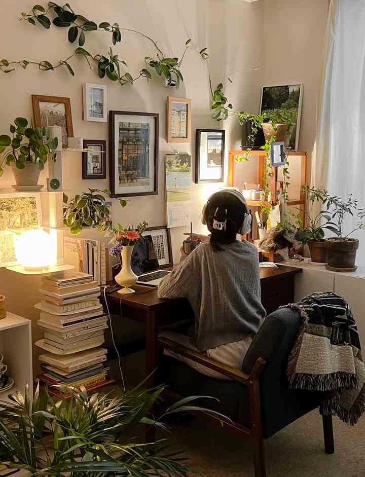 ナチュラルな色調の書斎空間、机と複数の額縁、植物が配置され、居心地よい在宅勤務の雰囲気を醸し出すインテリア