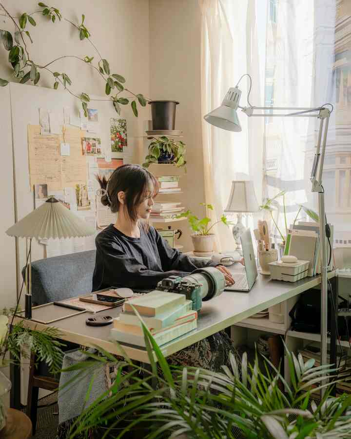 白いトーンのホームオフィス、机と多くの植物が配された落ち着いた自然な雰囲気の作業空間