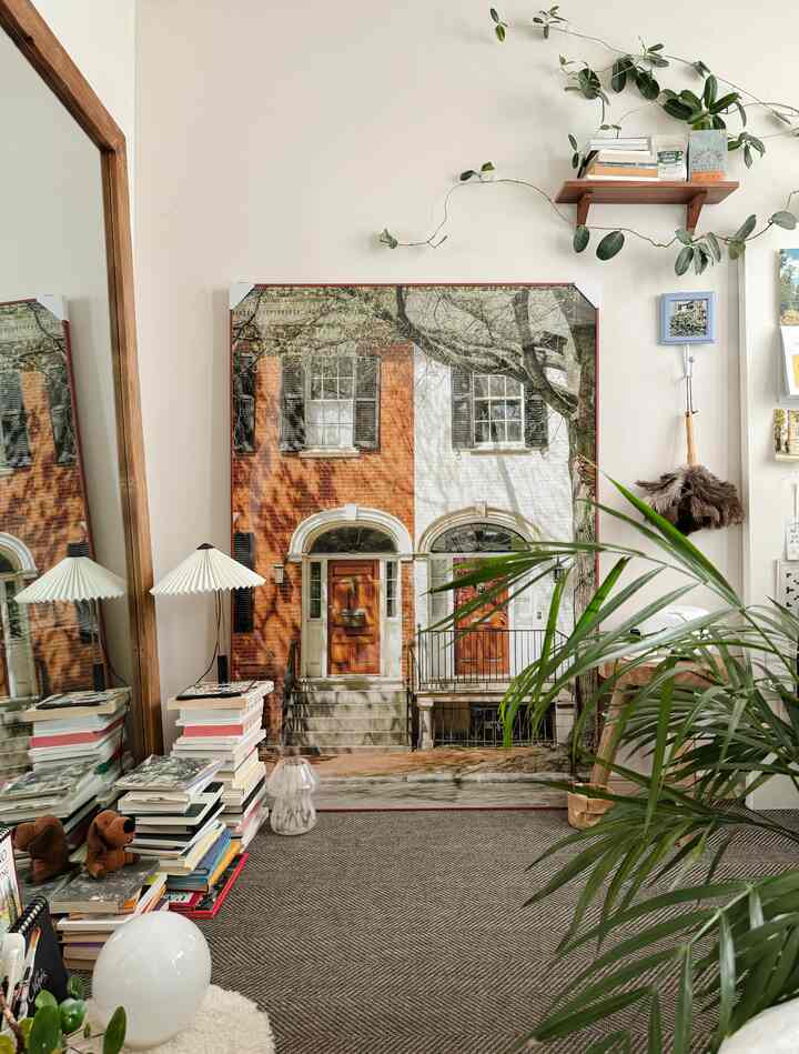 ナチュラルな色調の6畳の部屋、大きな額縁とラグ、木製棚、そして広い鏡が調和した温かみのある空間