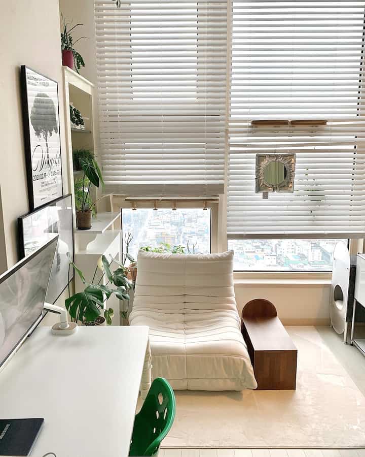 白とベージュの色調のリビング、一人用ラウンジチェアとサイドテーブルが配置されたミニマルで明るいインテリア