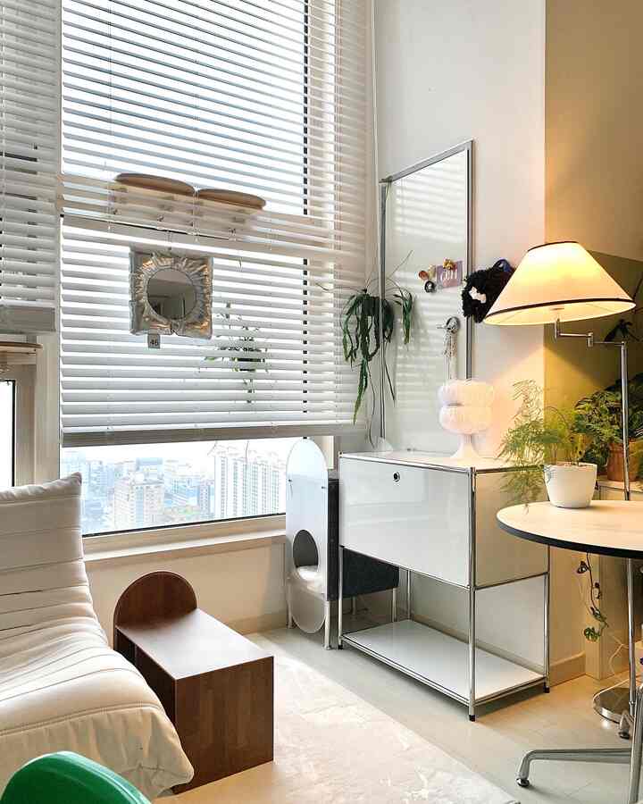 ホワイトとウッドトーンの調和が取れたリビング、ミッドセンチュリーモダンの収納キャビネットとミニキャットタワーが配置された印象的な空間