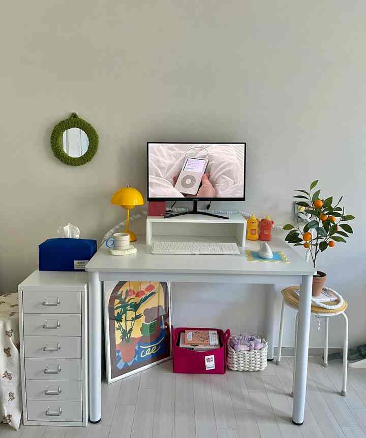 白を基調に黄色がアクセントのコンパクトなホームオフィス、シンプルなデスクと植物が配置された清潔感のあるインテリア