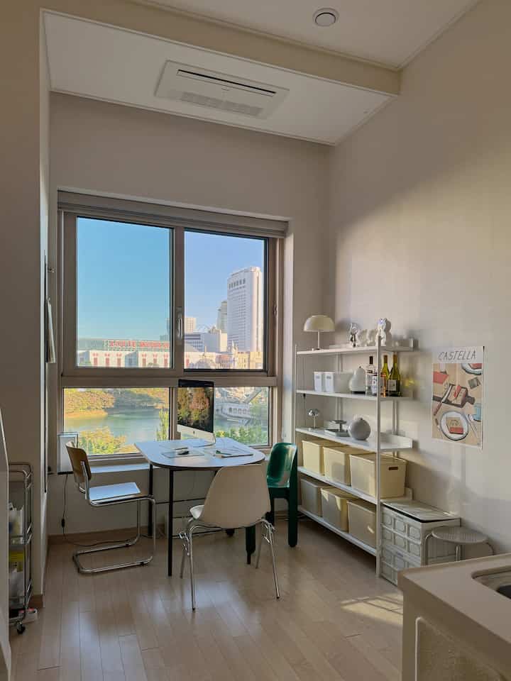 白とナチュラルカラーの狭いダイニングルーム、テーブルと椅子、壁棚と収納ボックスが配置された清潔感のあるインテリア