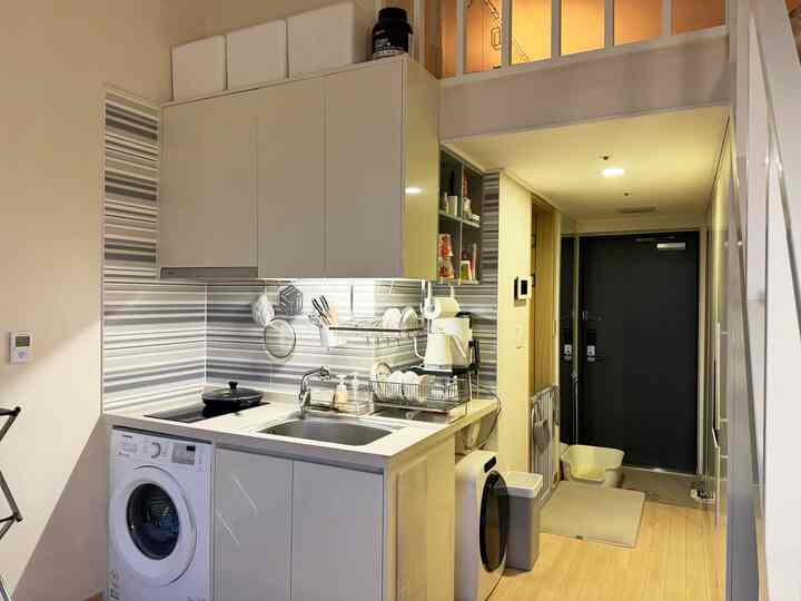 明るいホワイトとライトブラウンのL字型コンパクトキッチンと整理された玄関スペース