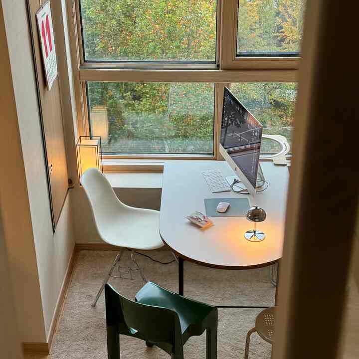 白と茶色の色調のコンパクトなホームオフィス、丸テーブルと椅子が配置され、落ち着いた雰囲気のインテリア