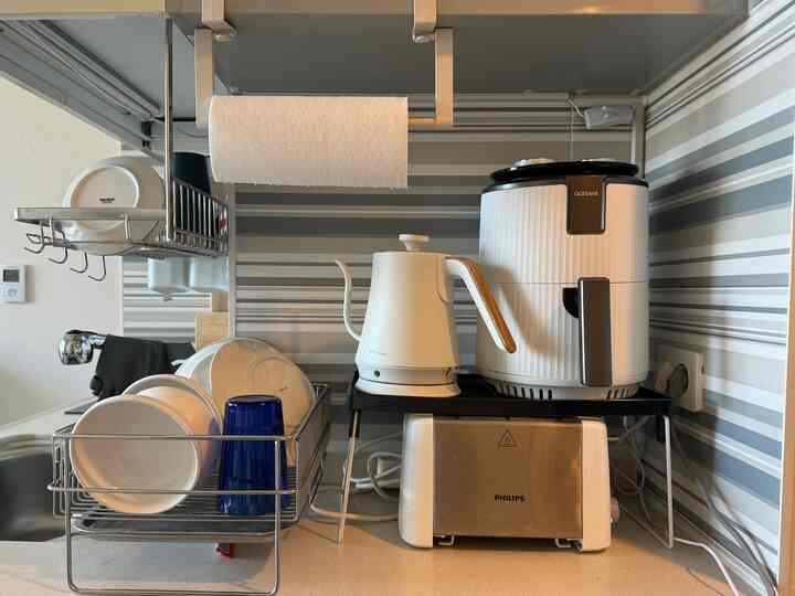 白とグレーのトーンのキッチン、皿やキッチン家電が整然と配置された実用的なインテリア