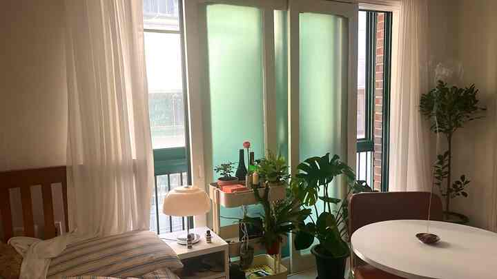 白と木目調が調和したワンルーム空間、ナイトテーブルとダイニングテーブルが配置された温かみのある雰囲気のインテリア