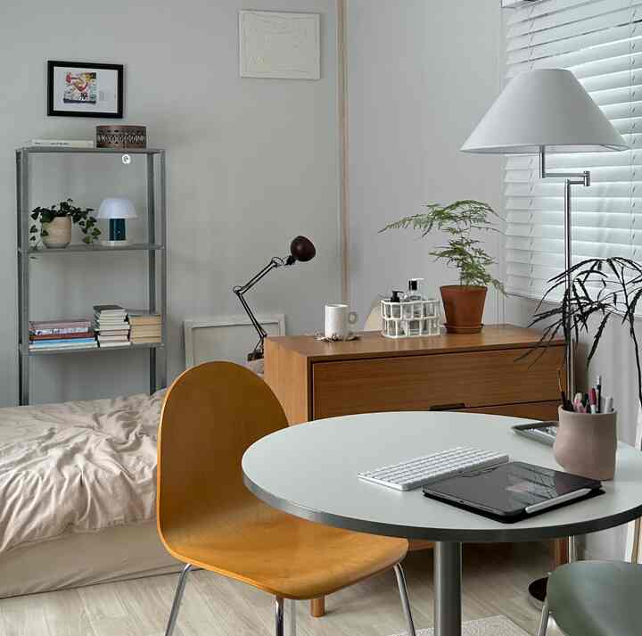 白とベージュのトーンのワンルーム、木製家具とデスク、植物が配置されたナチュラルモダンな印象的な空間