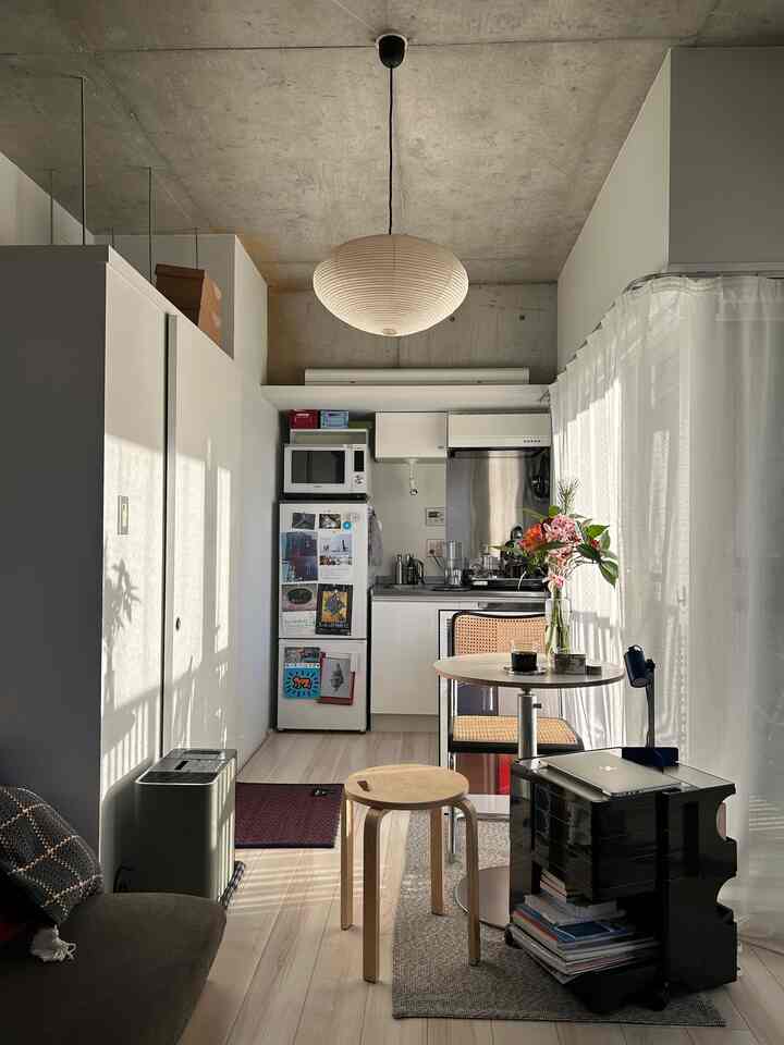 白とベージュのトーンでまとめられたコンパクトなキッチン、ナチュラルモダンの家具が配置された印象的な一人暮らし空間