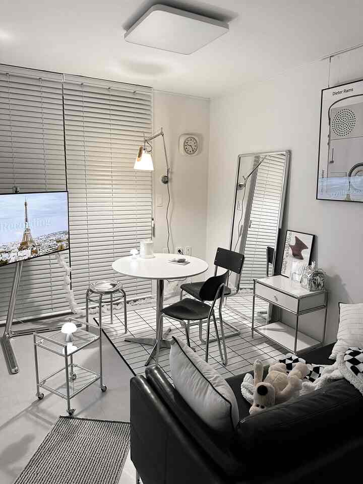 白と黒のモダンなリビングルーム、黒のレザーソファと白い丸テーブルと椅子が配置された印象的な空間