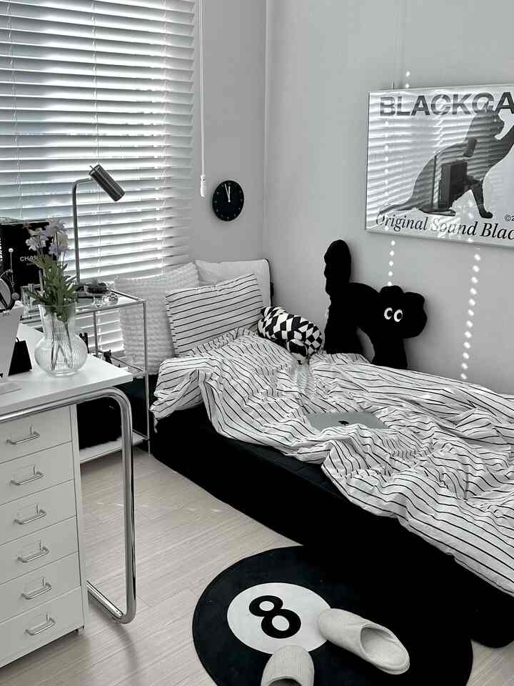 白と黒のトーンの寝室、デスクとブラインドが調和した印象的な一人暮らしの空間
