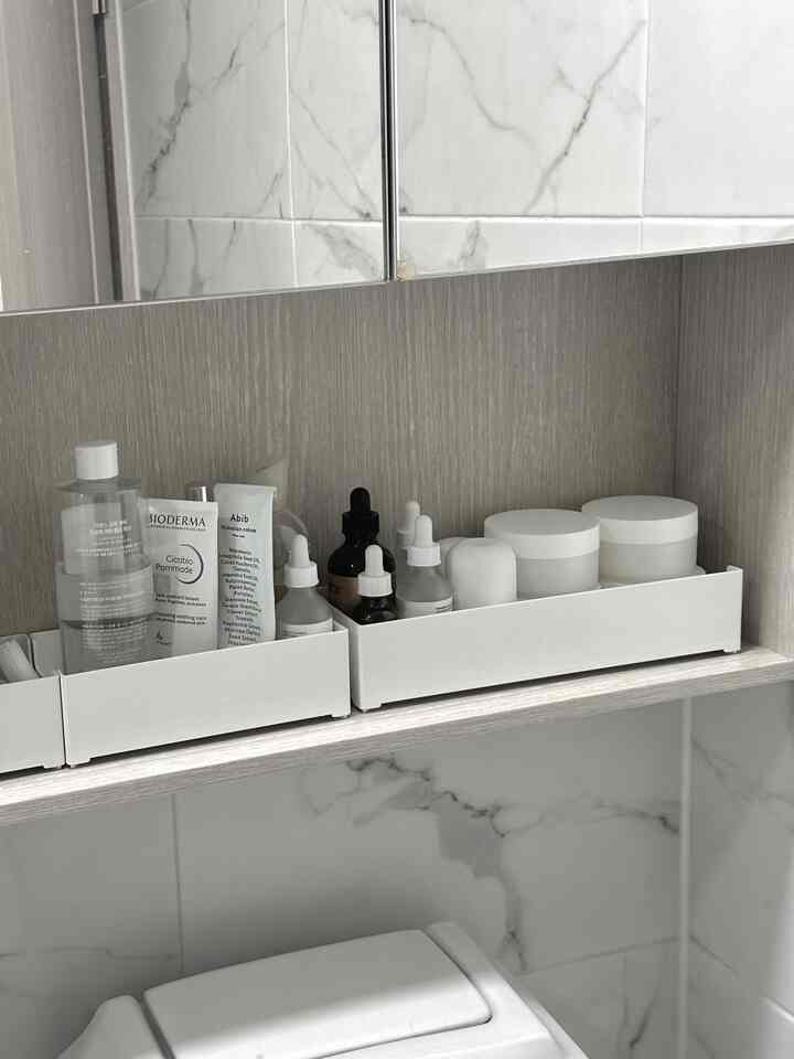 白とナチュラルカラーのバスルーム、スキンケア製品が整理箱に整頓された雰囲気のあるインテリア