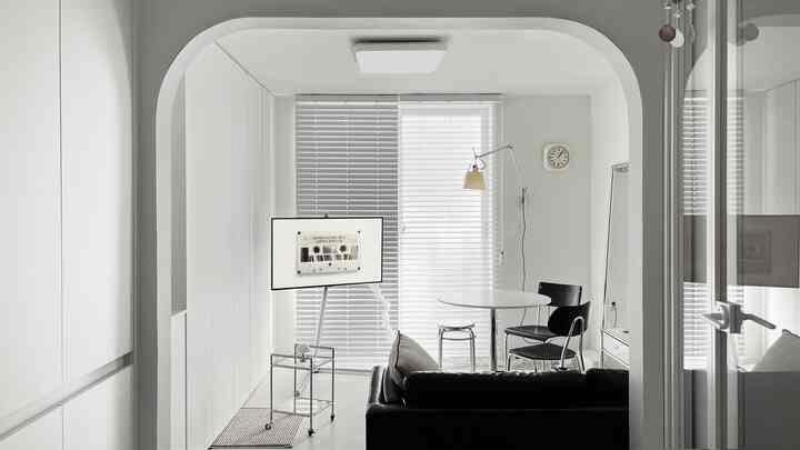 ホワイトとブラックのトーンのモダンなリビングルーム、洗練されたソファと丸いダイニングテーブルが配置されたミニマルな空間