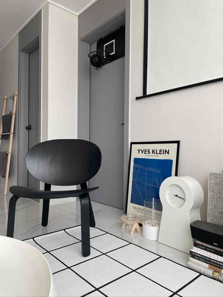 白を基調とした壁に黒い家具とポスターが置かれたミッドセンチュリーモダン風のウォークインクローゼット入口の空間