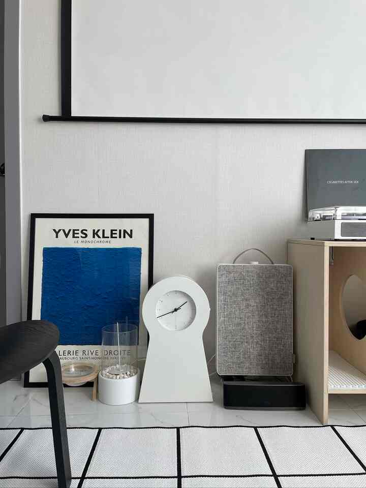 ホワイトとブルーの色調のリビング、額縁のポスター、時計、キャットハウスが配置されたナチュラルで清潔感のあるインテリア