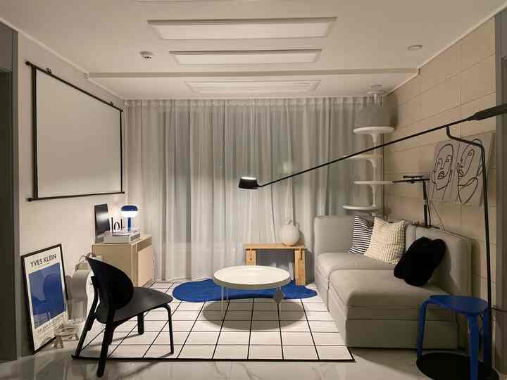 白と青のトーンのリビング、シフォンカーテンとモダンな家具が配置された雰囲気のある空間