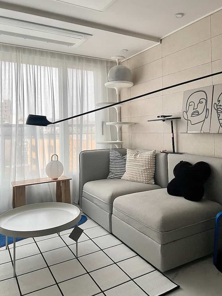 ホワイトとグレーのトーンのリビング、グレーのソファと丸いコーヒーテーブル、キャットタワーが配置されたモダンな空間