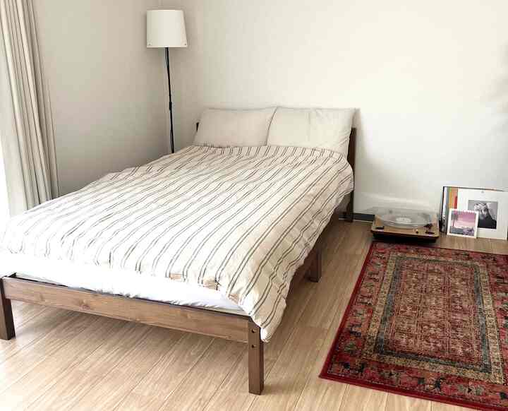 白と木目調が調和したシンプルでモダンな寝室、ベッドとラグが印象的な空間を作っている