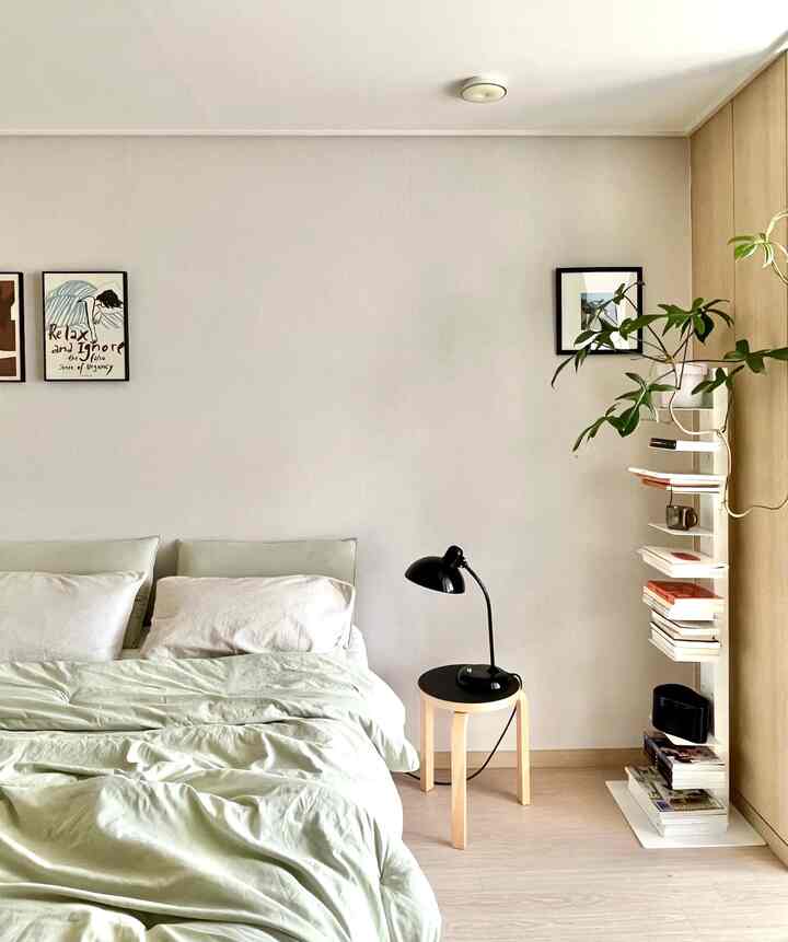 ナチュラルモダンの6畳寝室、快適なベッドとサイドテーブル、本棚と植物が配置されたシンプルなインテリア