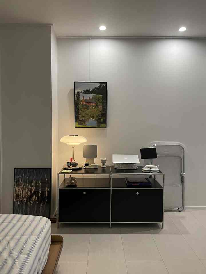 白い壁と床、黒いコンソールと木製ベッドがあるシンプルモダンな寝室のインテリア