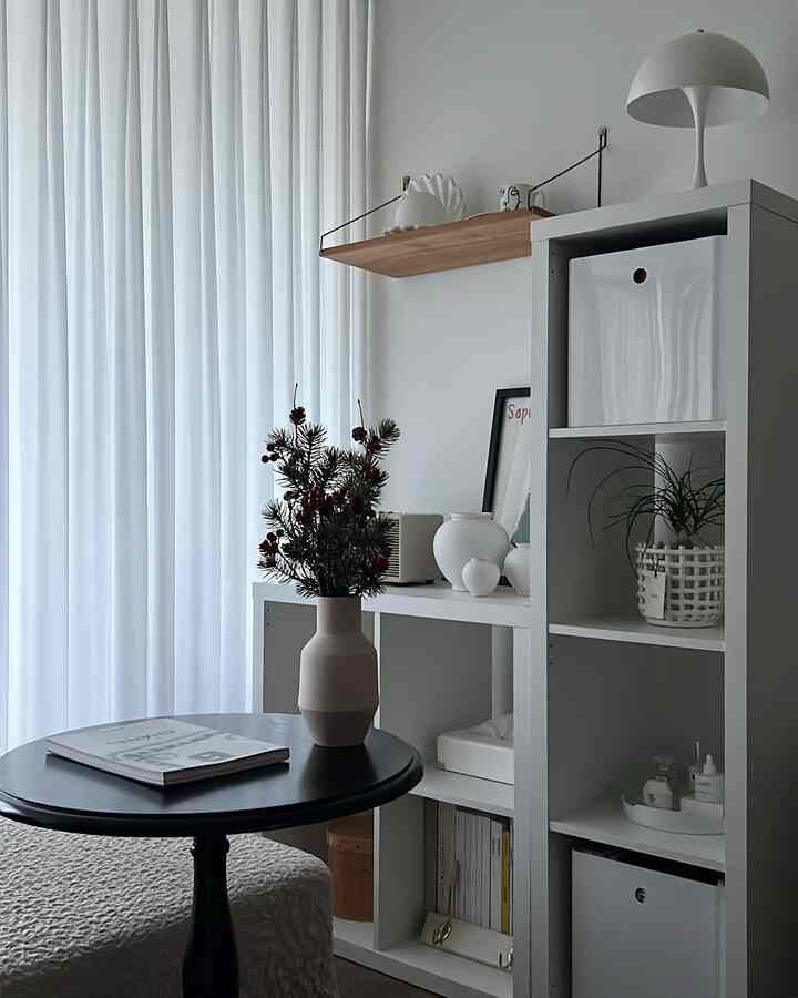 白とナチュラルトーンのキッチン空間、白い本棚と植物が配置されたモダンでシンプルなインテリア