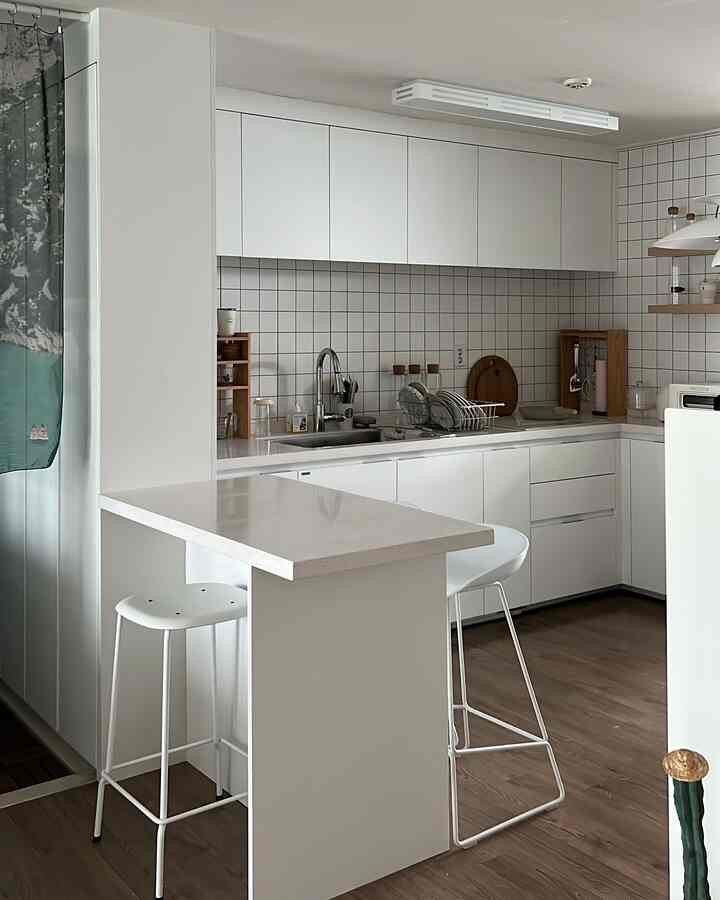 白と木目調が調和したキッチン、キッチンアイランドと白いダイニングチェアが配置されたモダンで自然な雰囲気のインテリア