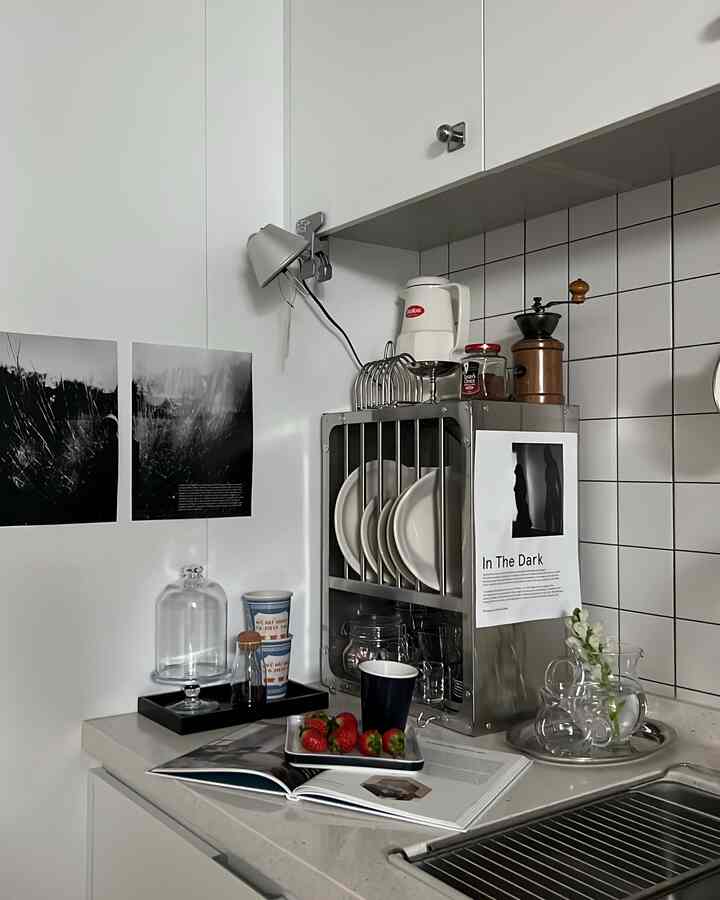 白いタイルと整頓された収納棚があるモダンなキッチン、カウンターにイチゴとカップが配置されている