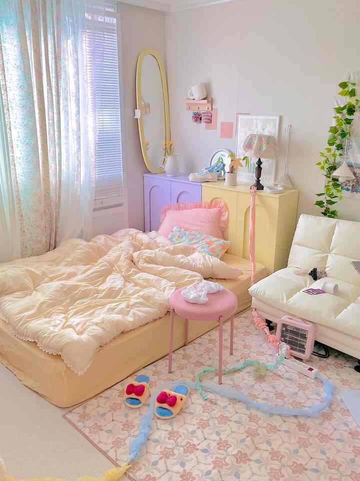 柔らかなベージュとピンクの色調の寝室、フレームのないクイーンベッドとクリーム色のソファが配置された居心地の良い空間