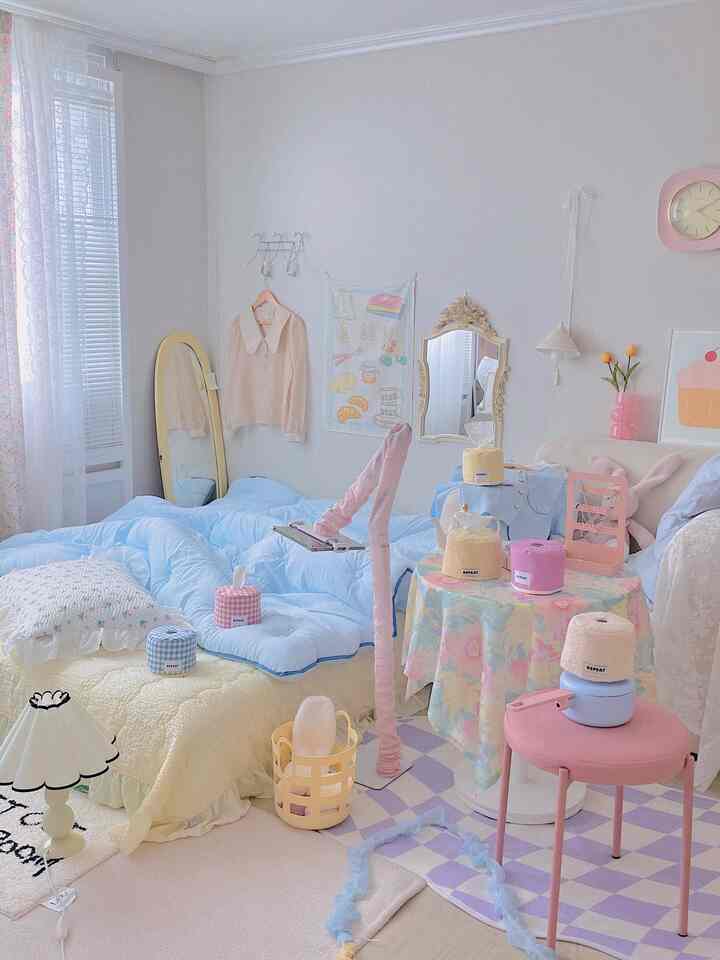 白い壁と青い寝具のある6畳の寝室で、ピンクのスツール、ナイトテーブル、鏡、壁時計が調和した雰囲気のあるインテリア