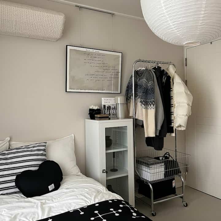 ホワイトとブラックのシンプルモダンな寝室、ハンガーラックとキャビネットが配置された居心地の良い狭い空間